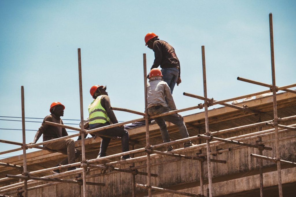 Construction workers wearing safety gear on scaffolding under clear skies in Nairobi, Kenya.