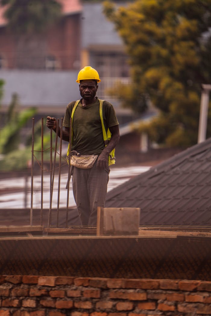 Construction worker in safety gear on a rooftop, focused on building work.